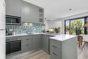 eine Küche mit weißen Geräten und ein Esszimmer in der Unterkunft 3 2 Katharina Street Noosa Heads in Noosa Heads + 6 Fotos