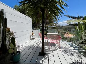 een terras met een palmboom en een tafel en stoelen bij Scandi Beach apartment in Avalon