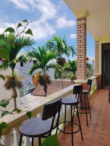 a balcony with chairs and tables and palm trees at Hidden Hue Homestay in Hue +117 photos