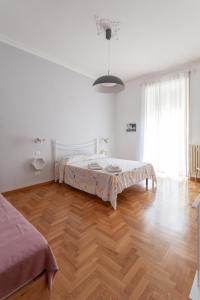 Habitación blanca con cama y suelo de madera. en Il Melograno Holiday House, en Roma