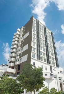 a tall white building with trees in front of it at The Signature Serviced Suites Puchong in Puchong