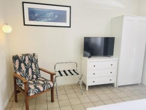 ein Wohnzimmer mit einem Stuhl und einem TV auf einer Kommode in der Unterkunft Paradise Court Holiday Units in Airlie Beach