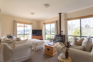 een woonkamer met witte banken en een tv bij Norfolk Bay Retreat - views over the sea and vines 