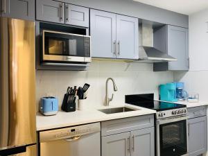 een keuken met witte kasten, een wastafel en een magnetron bij A Romantic Studio with Full Kitchen & AC-141 in Canmore