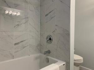 a white bathroom with a tub and a toilet at A Romantic Studio with Full Kitchen & AC-141 in Canmore +10 photos