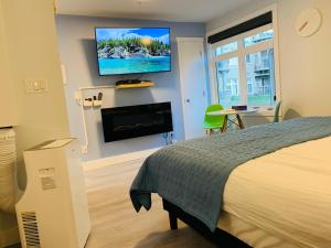 a bedroom with a bed and a flat screen tv on the wall at A Romantic Studio with Full Kitchen & AC-141 in Canmore