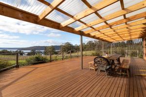 a wooden deck with a table and chairs on it at Norfolk Bay Retreat - views over the sea and vines 