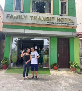 two people standing in front of a green building at Family Transit Hotel in Thach Loi