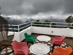a balcony with colorful chairs and tables on a balcony at Hotel Le Halcyon Kasauli in Solan