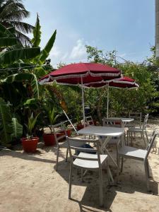 a group of tables and chairs with an umbrella at Gaskara Guesthouse in Shaviyani Atoll
