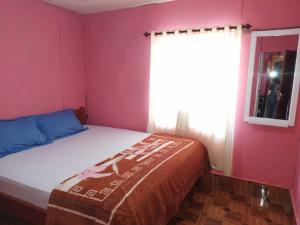 Kristian Homestay في Bajawa: غرفة نوم صغيرة مع سرير مع نافذة