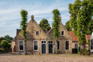 Slaaphutje BuitenWedde Westerwolde في Wedde: منزل من الطوب القديم مع اللبي ينمو عليه