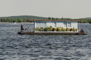 una persona de pie en un barco de la casa en el agua en feststehendes Hausboot en Kolonie Zern