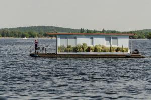 a person standing on a house boat on the water at feststehendes Hausboot in Kolonie Zern