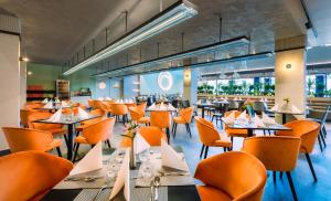 a restaurant with orange chairs and tables and tablesktop at Hunguest Bük - ex Répce és Répce Gold in Bük