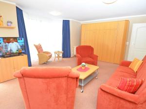 a living room with orange chairs and a tv at Ferienwohnungen Schulte in Baabe