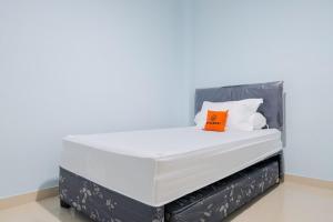 1 cama blanca grande con almohada naranja en la parte superior en KoolKost Syariah near Green Pramuka Square Mall - Minimal Stay 6 Nights en Yakarta