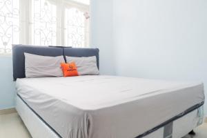 Una cama blanca con una almohada naranja. en KoolKost Syariah near Green Pramuka Square Mall - Minimal Stay 6 Nights en Yakarta