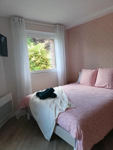 Un dormitorio con una cama con sábanas rosas y blancas y una ventana. en Les chambres du Vert Galant Rez de jardin en Verlinghem