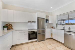 a kitchen with white cabinets and stainless steel appliances at Commodore 7 80 Noosa Parade in Noosa Heads