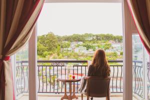 kobieta siedząca przy stole patrząca przez okno w obiekcie Lien Huong Hotel w mieście Da Lat