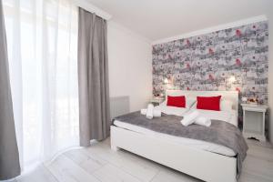 1 dormitorio con cama blanca y almohadas rojas en Villa Rose Garden, en Nyíregyháza