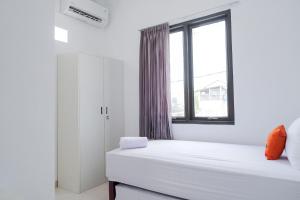 ein weißes Zimmer mit einem Bett und einem Fenster in der Unterkunft KoolKost near Jalan Veteran Raya (Minimum Stay 6 Nights) in Jakarta