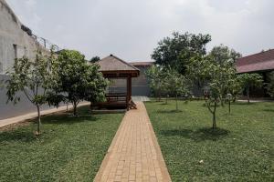 einen Ziegelweg in einem Garten mit Bäumen und einem Pavillon in der Unterkunft KoolKost near Jalan Veteran Raya (Minimum Stay 6 Nights) in Jakarta