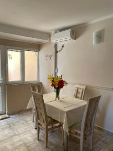 a dining room with a table with a vase of flowers on it at Apartman Pijavica in Bijela