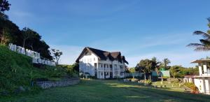 a large white house with a grass yard at Alta Vista Ilocandia Inc. in Pagudpud