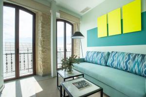 a living room with a blue couch and large windows at Sercotel Sevilla Guadalquivir Suites in Seville