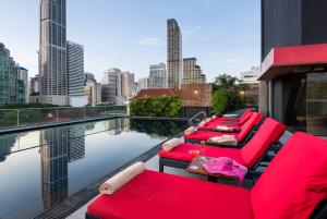 a row of red chairs and tables on a hotel rooftop at Maitria Mode Sukhumvit 15 Bangkok - A Chatrium Collection in Bangkok