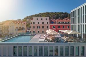 a pool on top of a building with chairs and umbrellas at Hotel Ambasador in Split