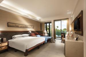 三亜市にあるWanda Realm Resort Sanya Haitang Bayのベッドとテレビが備わるホテルルームです。