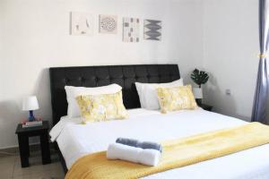 sypialnia z dużym białym łóżkiem z żółtymi poduszkami w obiekcie North Manor Nakuru w mieście Nakuru