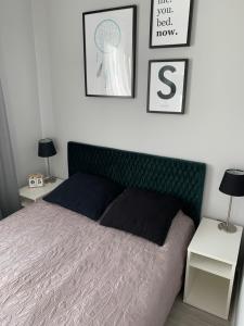 a bedroom with a bed with a green headboard at Apartament Abrahama 40 in Gdynia