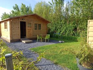 a cabin in a garden with a table and chairs at Verton, Gîte Les chalets du Fliers Meublés de tourisme classés 2 étoiles plage de BERCK SUR MER in Verton
