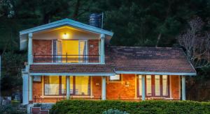 a house with a balcony on top of it at The Orange Home in Kotagiri