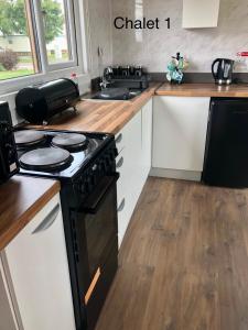 a kitchen with a black stove and a sink at Atlanta Ceder Wood Chalet in Mablethorpe