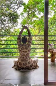 a woman sitting on a porch with her arms in the air at Gal Oruwa Resort in Dambulla