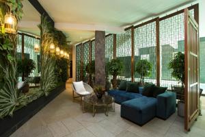 un salon avec un canapé bleu et des plantes dans l'établissement Le Centell Hotel & Spa, à Antananarivo