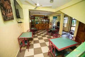 ein Restaurant mit Tischen und Stühlen und einem Schachbrettboden in der Unterkunft Bombay Hotel in Accra