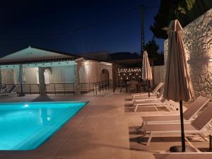 ein Pool mit Stühlen und Sonnenschirmen in der Nacht in der Unterkunft Stark - AzulenaCalpe in Calpe