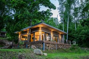 a log cabin in the woods with lights at Lapsu ciems in Sece