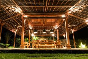a wooden pavilion with a table and chairs under it at Alami Boutique Villas & Resort in Tabanan