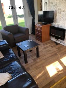 a living room with a couch and a tv and a table at Atlanta Ceder Wood Chalet in Mablethorpe