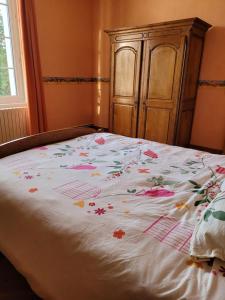 uma cama com uma colcha floral com um armário de madeira em Chambre chez l'habitant 3 em Biville-la-Baignarde
