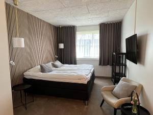 a bedroom with a bed and a chair and a window at Hotel Sov Godt Herning in Herning