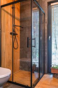 a glass shower stall in a bathroom with a tub at Stara Izba samotnia blisko natury in Aleksandria