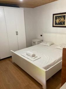 a white bed in a room with white cabinets at Bujtina Arturi in Valbonë